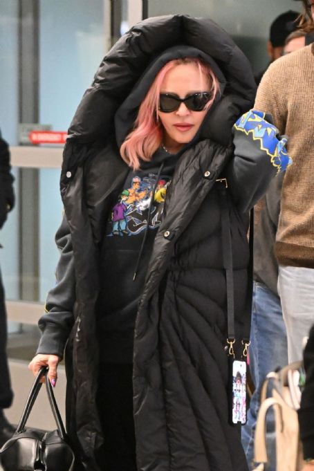 Madonna, 64, Covers Up Her Pink Hair In Oversized Graphic Jacket at JFK Airport in New York